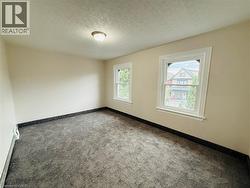 Carpeted spare room featuring a textured ceiling and a baseboard heating unit - 
