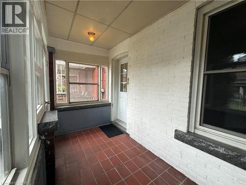 Unfurnished sunroom featuring brick wall, tile patterned floors, and a paneled ceiling - 24 Somerset Avenue, Hamilton, ON -  With Exterior