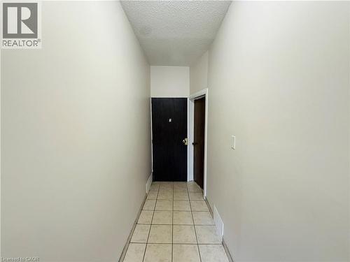 Hallway with light tile patterned floors and a textured ceiling - 24 Somerset Avenue, Hamilton, ON - Indoor Photo Showing Other Room