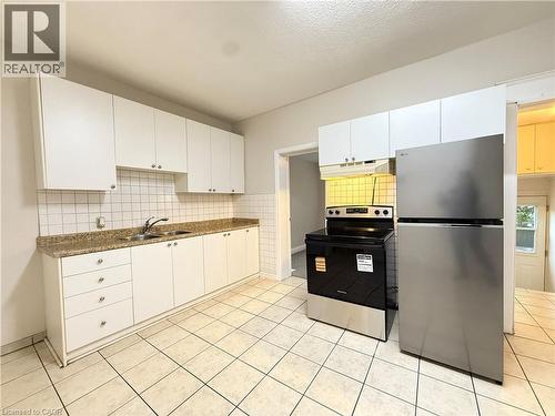 Kitchen featuring appliances with stainless steel finishes, backsplash, dark countertops, and white cabinetry - 24 Somerset Avenue, Hamilton, ON - Indoor Photo Showing Kitchen With Double Sink