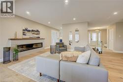 Living room featuring a glass covered fireplace, light wood-style flooring, and recessed lighting - 