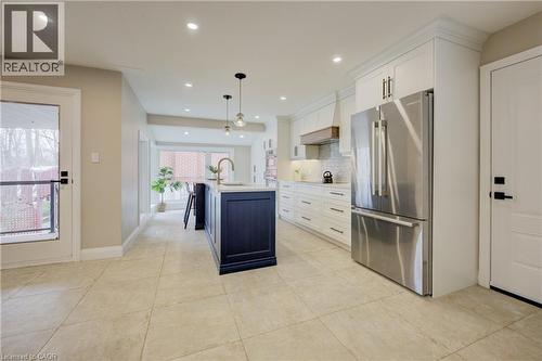 Kitchen featuring freestanding refrigerator, white cabinets, an island with sink, hanging light fixtures, and tasteful backsplash - 279 Ferndale Place, Waterloo, ON - Indoor Photo Showing Kitchen With Upgraded Kitchen