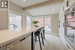 Kitchen featuring stainless steel appliances, light stone counters, vaulted ceiling, recessed lighting, and plenty of natural light - 