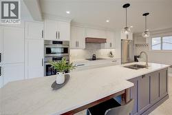 Kitchen featuring appliances with stainless steel finishes, decorative light fixtures, light stone countertops, white cabinetry, and recessed lighting - 