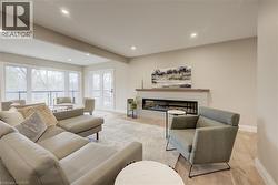 Living room with a glass covered fireplace, wood finished floors, recessed lighting, and beam ceiling - 