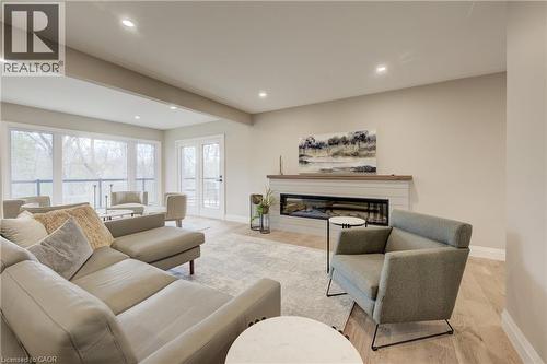 Living room with a glass covered fireplace, wood finished floors, recessed lighting, and beam ceiling - 279 Ferndale Place, Waterloo, ON - Indoor Photo Showing Living Room With Fireplace