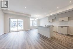 Kitchen with light wood-style floors, recessed lighting, an island with sink, open floor plan, and white cabinetry - 