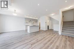 Unfurnished living room featuring light wood-style flooring, stairs, and recessed lighting - 