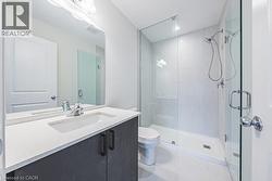 Full bath with vanity, a stall shower, and light tile patterned floors - 