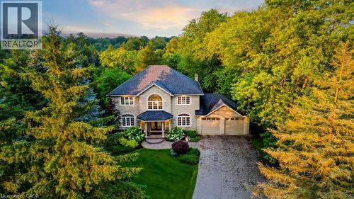 View of front of house with stone siding, a chimney, driveway, a garage, and a forest view - 1525 Dickie Settlement Road, Cambridge, ON - Outdoor