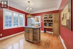 Kitchen with high end refrigerator, brown cabinets, light wood-style floors, and ornamental molding - 