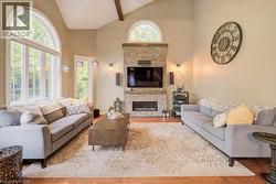 Living room featuring a fireplace, high vaulted ceiling, and wood finished floors - 