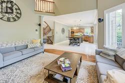 Living area featuring a chandelier, stairs, light wood finished floors, crown molding, and a high ceiling - 
