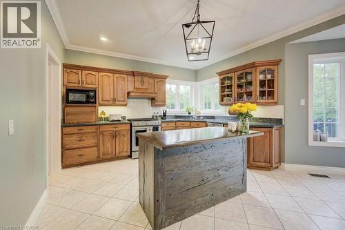 Kitchen featuring stainless steel range with gas stovetop, black microwave, dark countertops, glass insert cabinets, and brown cabinetry - 1525 Dickie Settlement Road, Cambridge, ON - Indoor Photo Showing Kitchen
