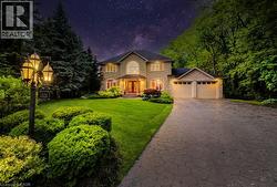 View of front of property featuring stone siding, a garage, a yard, and driveway - 