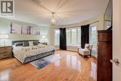 Bedroom featuring light wood finished floors, a chandelier, and a textured ceiling - 
