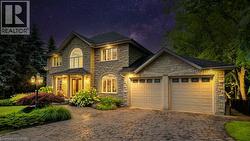 View of front facade featuring stone siding, decorative driveway, and a garage - 