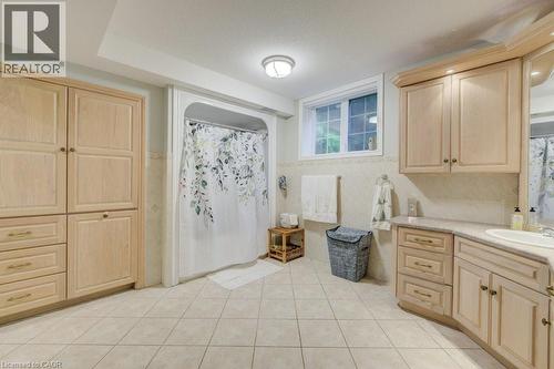 Full bath featuring tile patterned flooring, vanity, tile walls, curtained shower, and wainscoting - 1525 Dickie Settlement Road, Cambridge, ON - Indoor