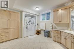 Full bath featuring tile patterned flooring, vanity, tile walls, curtained shower, and wainscoting - 