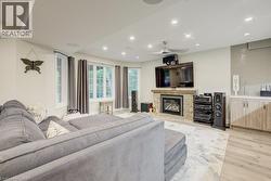 Living area with light wood-style flooring, recessed lighting, and a stone fireplace - 
