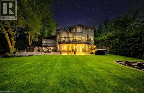 Back of house at twilight with a patio, a balcony, a hot tub, stone siding, and a yard - 1525 Dickie Settlement Road, Cambridge, ON - Outdoor With Deck Patio Veranda