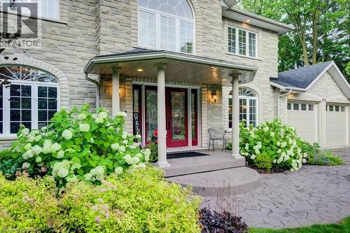 Entrance to property featuring stone siding, covered porch, and an attached garage - 1525 Dickie Settlement Road, Cambridge, ON - Outdoor