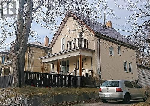 View of property exterior with brick siding, a chimney, covered porch, and a balcony - 134 Courtland Avenue E, Kitchener, ON 