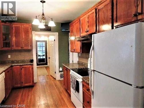 Kitchen with white appliances, dark wood finished floors, brown cabinets, decorative light fixtures, and a chandelier - 134 Courtland Avenue E, Kitchener, ON 