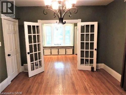 Unfurnished dining area with wood finished floors, a chandelier, and french doors - 134 Courtland Avenue E, Kitchener, ON 