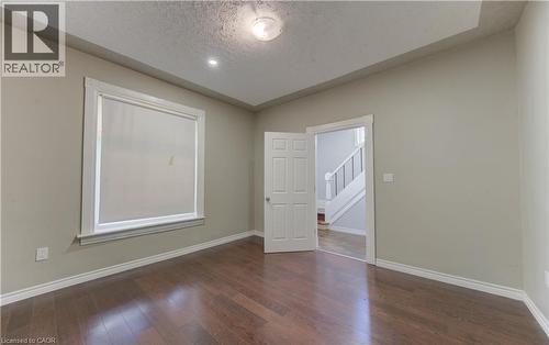 Unfurnished room featuring dark wood-style floors and a textured ceiling - 138 Courtland Avenue E, Kitchener, ON 