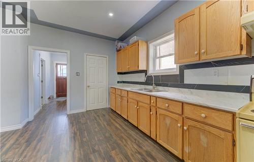 Kitchen with tasteful backsplash, plenty of natural light, dark wood-style flooring, white stove, and recessed lighting - 138 Courtland Avenue E, Kitchener, ON 
