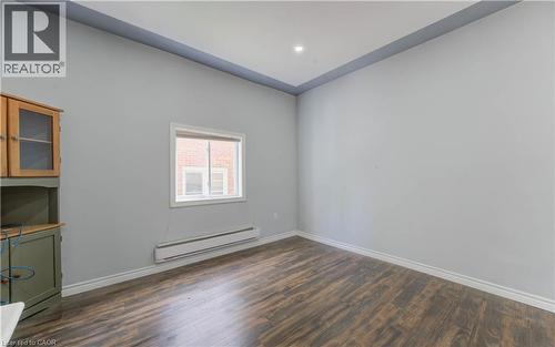 Unfurnished room with a baseboard heating unit, dark wood-style floors, and recessed lighting - 138 Courtland Avenue E, Kitchener, ON 