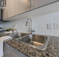 Interior details with dark stone countertops, backsplash, and a sink - 