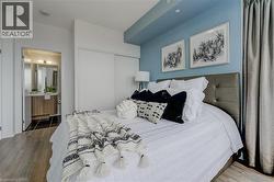 Bedroom with ensuite bath, wood finished floors, and a closet - 