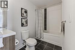Full bathroom featuring tile patterned flooring, baseboards, toilet, shower / tub combo with curtain, and vanity - 