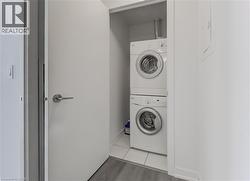 Laundry area featuring baseboards, stacked washer and clothes dryer, and light wood finished floors - 