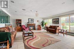 room featuring light tile patterned flooring, a glass covered fireplace, and a baseboard radiator - 