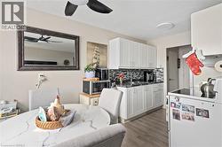 Kitchen with stainless steel microwave, a ceiling fan, backsplash, a sink, and wood finished floors - 