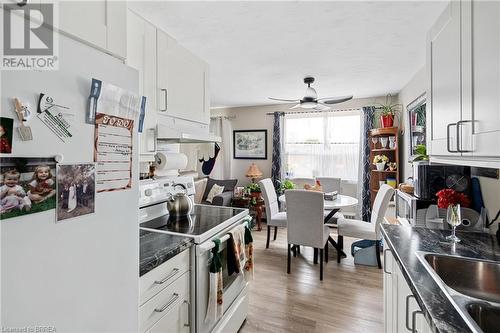 Kitchen featuring white appliances, under cabinet range hood, dark countertops, light wood-type flooring, and white cabinets - 485 Thorold Road Unit# 323, Welland, ON - Indoor Photo Showing Other Room