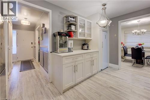 Kitchen with open shelves, glass insert cabinets, light wood-style flooring, white cabinets, and decorative light fixtures - 31 Bonfair Court, Kitchener, ON - Indoor