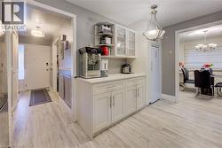 Kitchen with open shelves, glass insert cabinets, light wood-style flooring, white cabinets, and decorative light fixtures - 