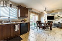 Kitchen with dark brown cabinetry, light tile patterned floors, open floor plan, hanging light fixtures, and dishwasher - 