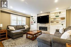 Living room featuring ornamental molding, a stone fireplace, wood finished floors, and recessed lighting - 