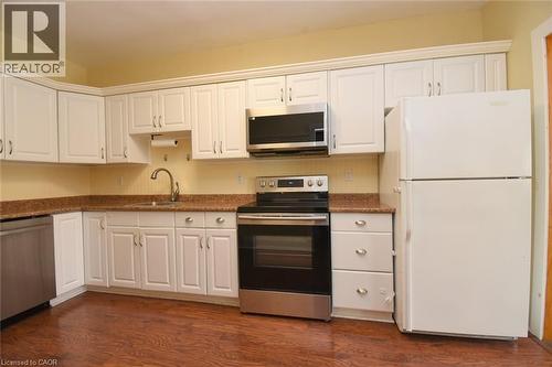 Kitchen with stainless steel appliances, white cabinetry, dark countertops, and dark wood finished floors - 82 Somerset Avenue, Hamilton, ON - Indoor Photo Showing Kitchen