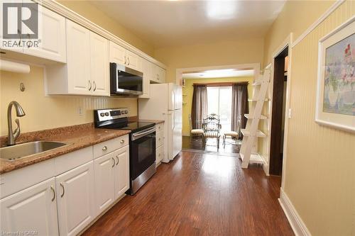 Kitchen with white cabinetry, stainless steel appliances, dark wood finished floors, and dark counters - 82 Somerset Avenue, Hamilton, ON - Indoor Photo Showing Kitchen
