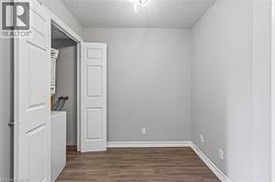 Laundry room with a textured ceiling, dark wood-type flooring, and stacked washer / drying machine - 