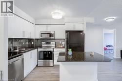 Kitchen featuring appliances with stainless steel finishes, light wood-style floors, tasteful backsplash, and white cabinets - 