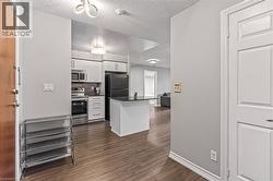 Kitchen featuring appliances with stainless steel finishes, white cabinets, dark countertops, a textured ceiling, and dark wood-style flooring - 