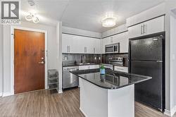 Kitchen featuring appliances with stainless steel finishes, wood finished floors, tasteful backsplash, and white cabinets - 