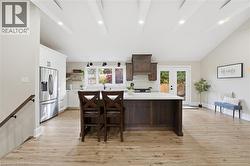 Kitchen with decorative backsplash, stainless steel refrigerator with ice dispenser, vaulted ceiling, light wood finished floors, and recessed lighting - 